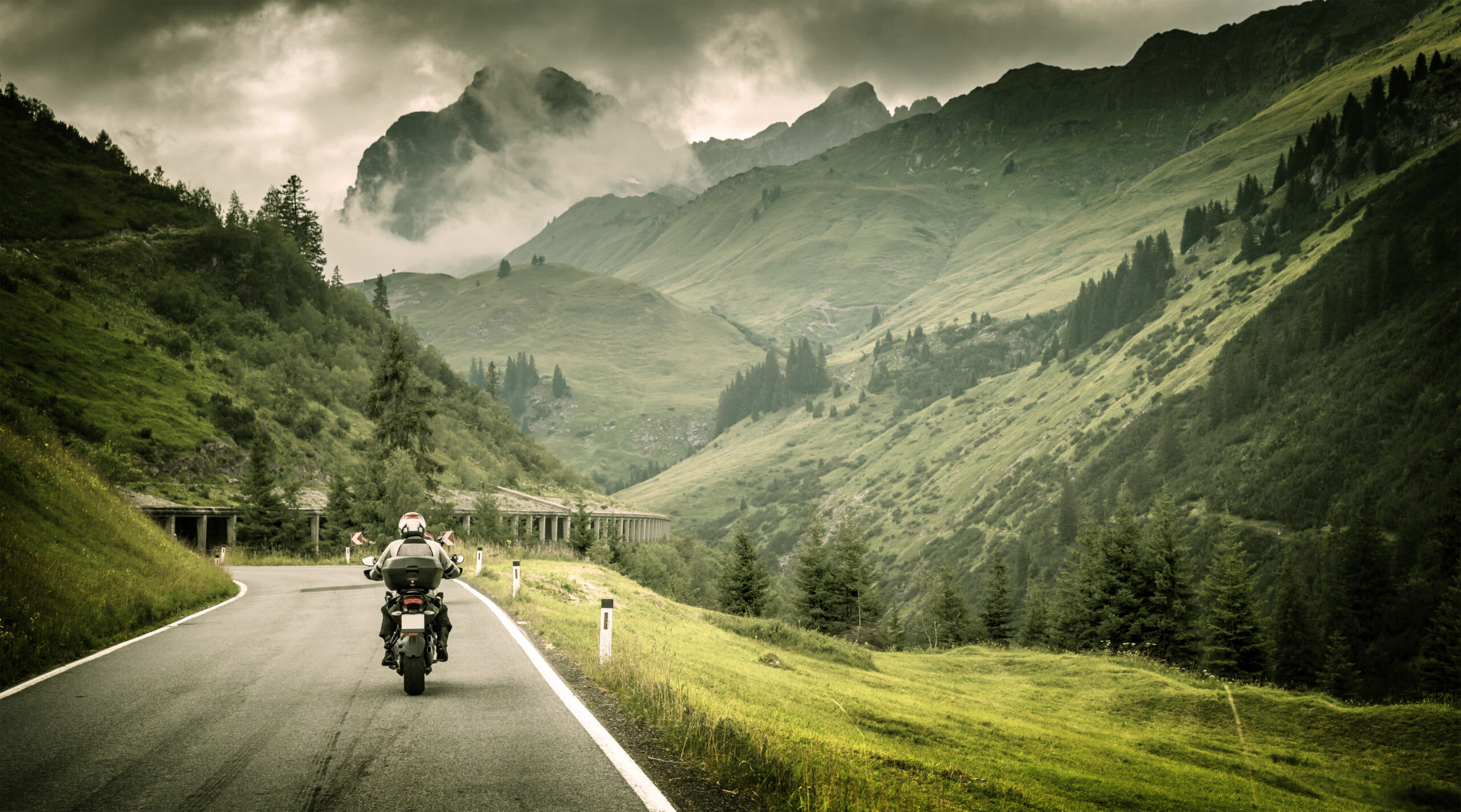 Motorcyclist on a mountainous highway, cold overcast weather,