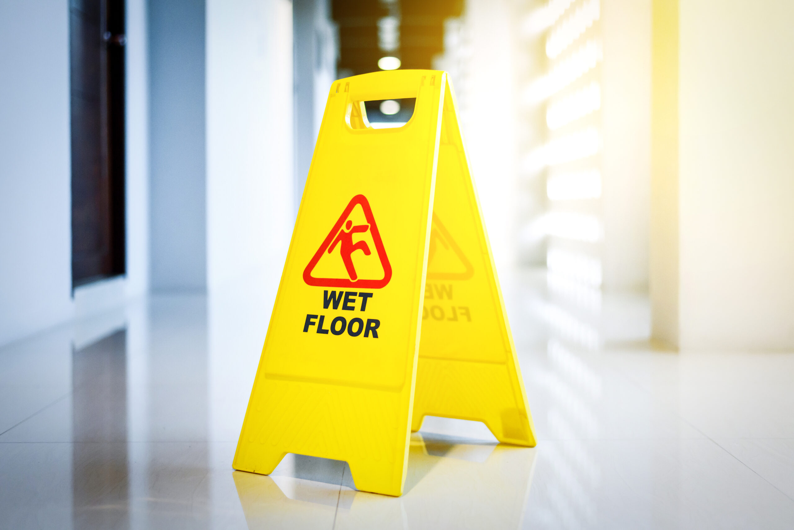 Wet floor warning sign on a tile floor warning people to be careful of slip and fall injuries