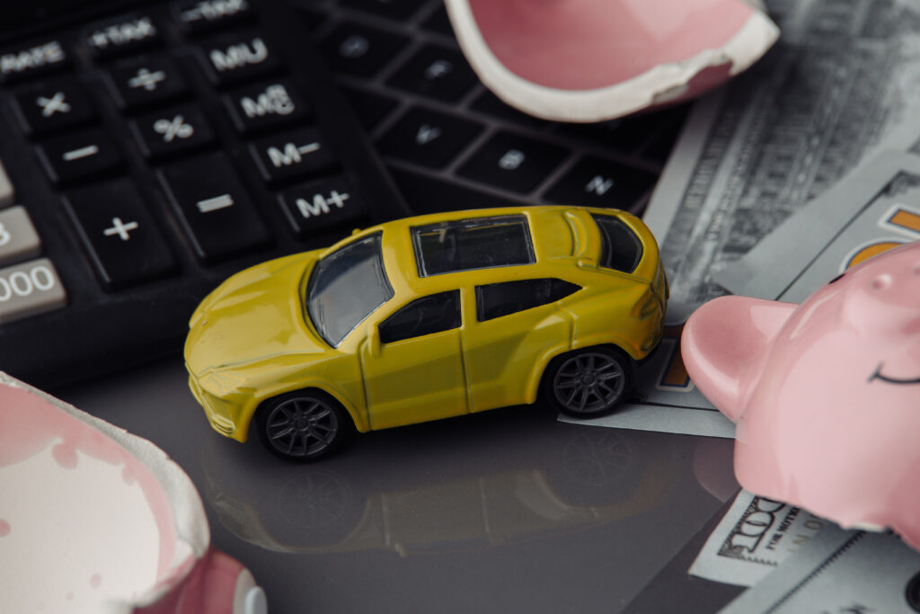 Yellow toy car close-up and dollars bills with broken pink piggy bank. Insurance concept