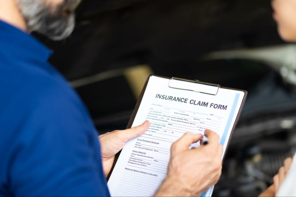 An insurance claims adjuster and a car accident victim look over an insurance claim form together.