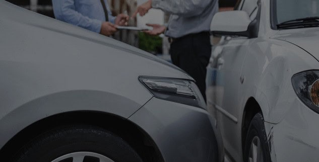Two cars stopped close to each other. Two people in the background are discussing and gesturing over a document.
